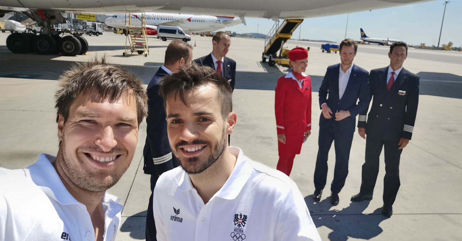 Martin Strempfl mit Badmintonspieler Luka Wraber vor der Austrian-Airlines-Maschine und Crew